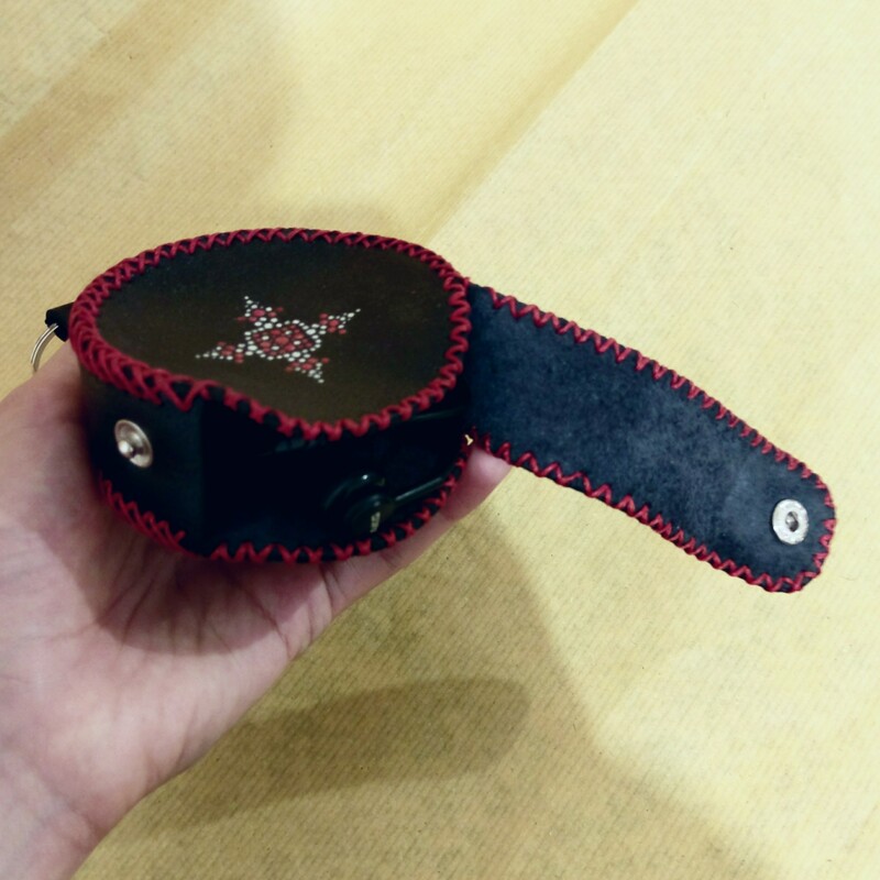 کیف هندزفری چرمی مشکی با طرح نقطه کوبی قرمز و نقره ای