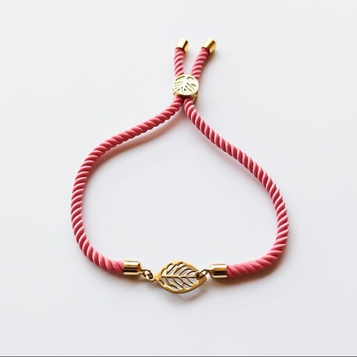 دستبند مدل دیما با پلاک برگ طلایی استیل و بند مارشال صورتی مناسب هدیه و روزمره