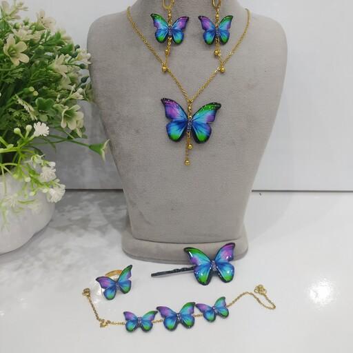 ست پنج تکه پروانه آبی بنفش آویز دار .شامل گردنبند،دستبند،گوشواره با اتصالات رنگ ثابت و گیرمو و انگشتر کیفیت معمولی