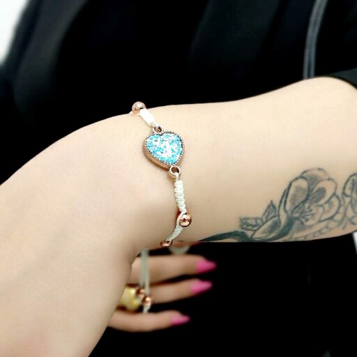 دستبند زنانه و دخترانه دستبافت با مهره های حدید طلایی توپی و نشان منشوری قلبی آبی روشن