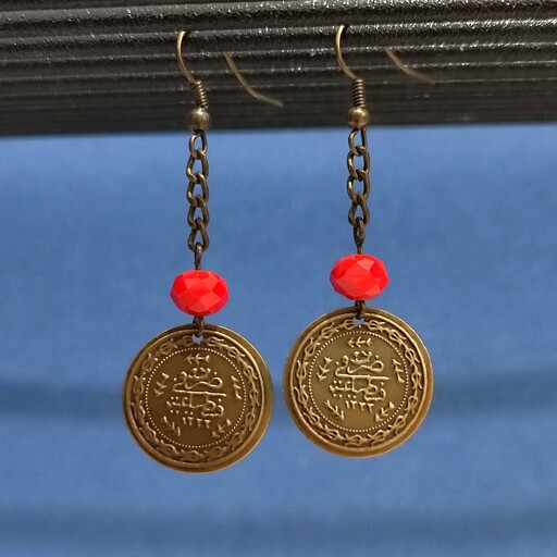 گوشواره با ترکیب  سکه برنزی و تک کریستال قرمز .  بصورت آویزی و  جفت می باشد