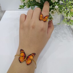 دستبند و انگشتر پروانه نارنجی رزینی.دستبند شامل یک پروانه چهارسانت با اتصالات رنگ ثابت و انگشتر هدیه کیفیت معمولی