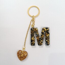 جاسوییچی یا اویز کلید طرح حروف انگلیسی M همراه با اویز قلب طلایی رزینی ایساتیس