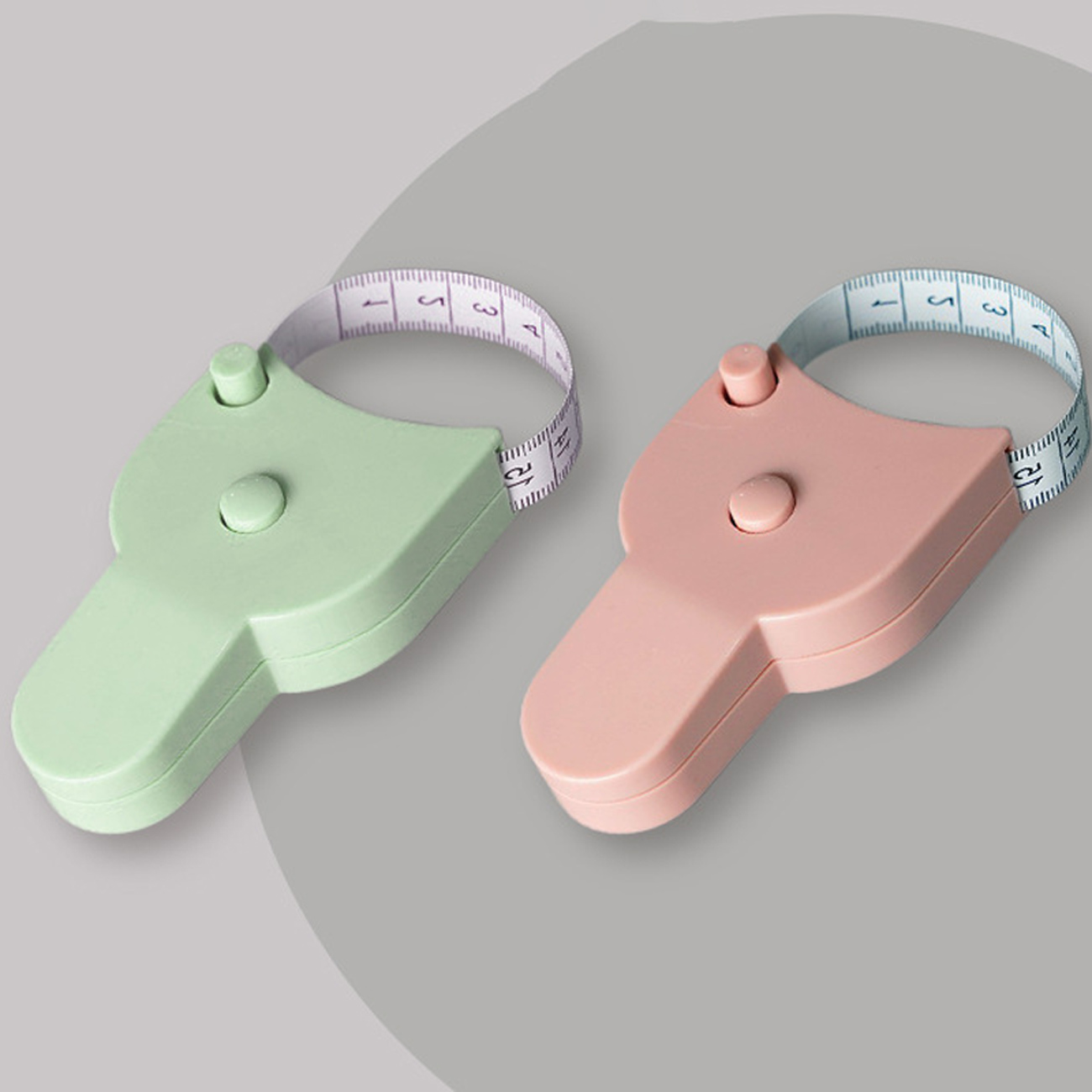 Two Y-shaped tape measures, one green and one pink, with white measuring tapes extended.