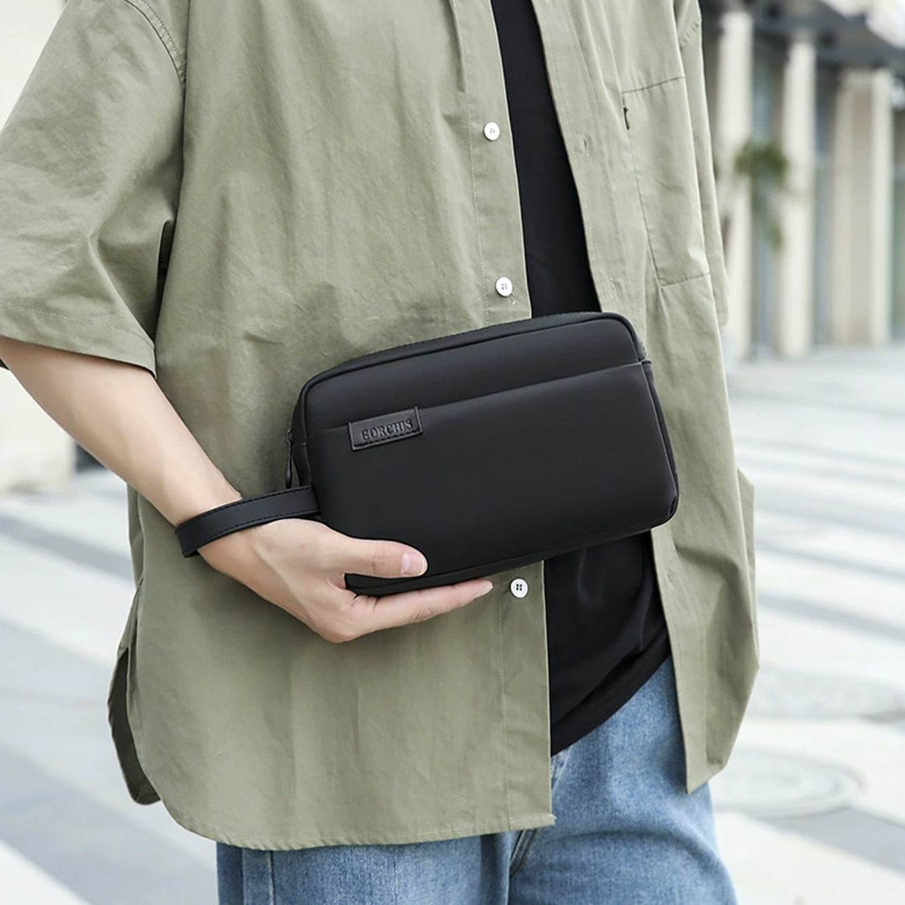 کیف دستی مردانه گورچیس مدل 2305 مشکی ضد آب با بند دستی، به همراه نشان تجاری.