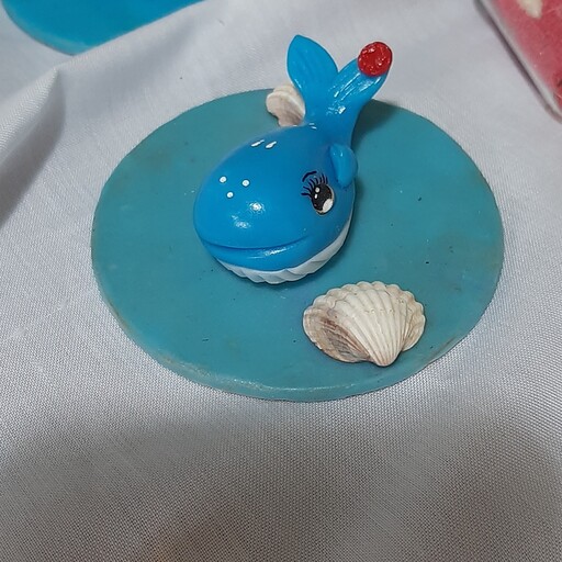 نمادسال.مجسمه نهنگ کوچولو.در رنگهای آبی صورتی بنفش ومشکی.ساخته شده باخمیرچینی 