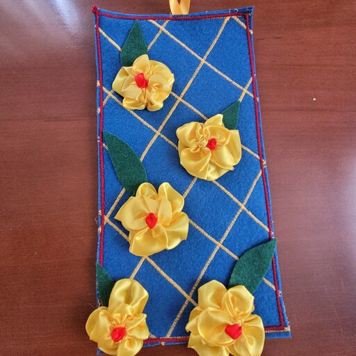 تابلو روباندوزی با گل های زرد وزمینه آبی دارای پنج گل وپنج برگ  گل از روبان  وزمینه  نمد است 