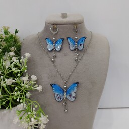 نیم ست پروانه آبی سفید با اتصالات نقره ای و رنگ ثابت شامل گردنبند و گوشواره آویزدار