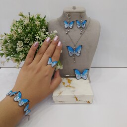 ست پنج تکه پروانه آبی سفید با اتصالات نقره ای شامل گردنبند،دستبند،گوشواره اتصالات رنگ ثابت و گیرمو انگشتر کیفیت معمولی