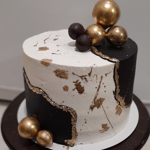 کیک تولد خامه ای مشکی طلایی با تزیین گوی شکلاتی