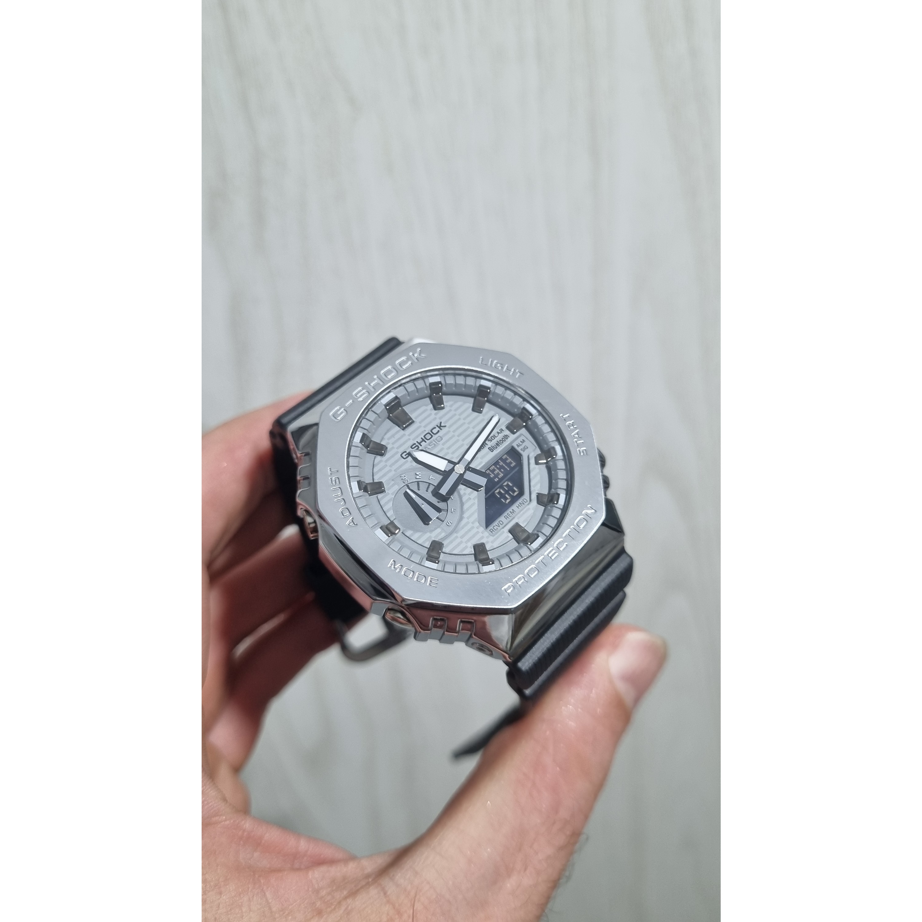 ساعت مچی جی شاک مدل GM-2100B-3A (جیشاک GShock) تنظیم اتوماتیک با پایتخت کشورها ،اتولایت اتوماتیک دور استیل نقره ای