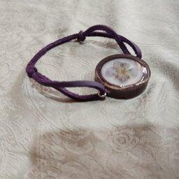 دستبند رزینی با گل خشک طبیعی و بند تریشه چرم بنفش رنگ