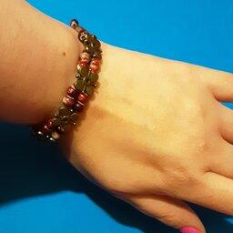 دستبند بافت دو ردیف،دارای سنگهای قرمز تیره و روشن و گلهای برنزی کار شده در میان دستبند،ساخت هند
