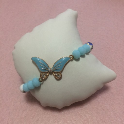 دستبند کشی مهره سرامیکی گلدار و مهره کریستالی مات آبی با پلاک پروانه آبی بزرگ زرین ساز