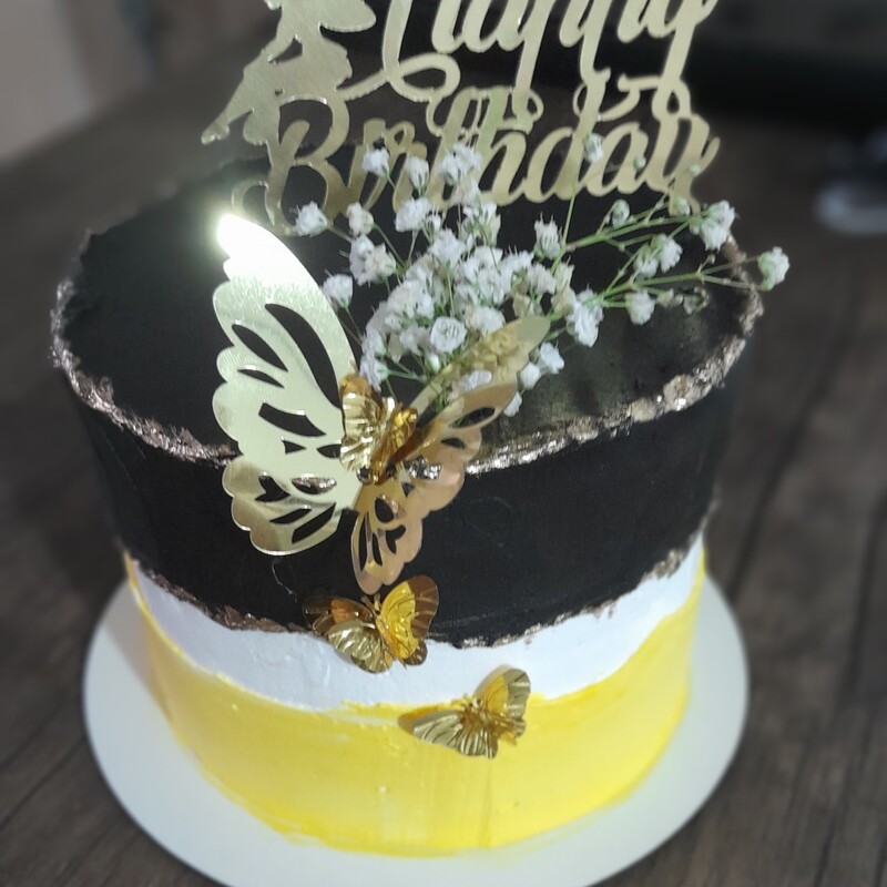 کیک خامه ای تولد.رنگ زرد و مشکی با تزیین پروانه