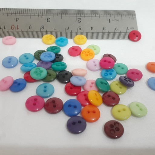 پک 25 تایی دکمه های رنگی رنگی کوچک یک سانتی در رنگهای مختلف دو سوراخ طبق عکس پلاستیکی