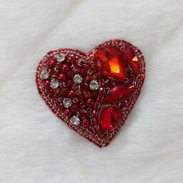 سنجاق سینه جواهر دوزی طرح(قلب)و پشت تماماً چرم و به رنگ قرمز براق می‌باشد.