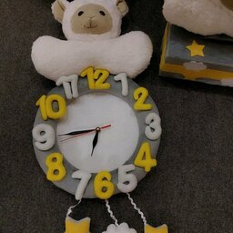 ساعت دیواری اتاق کودک، دارای اویز، جنس خز بره ای، دارای صفحه ساعت چوبی