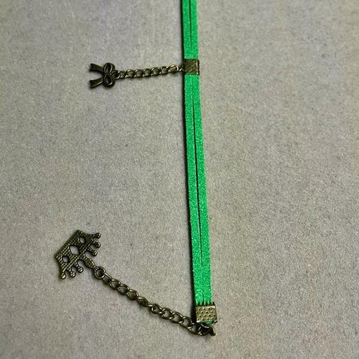 دستنبند تریشه چرمی مدل ساده سبز همراه با خرج کار برنزی طرح تاج و پاپیون و زنجیر برنزی